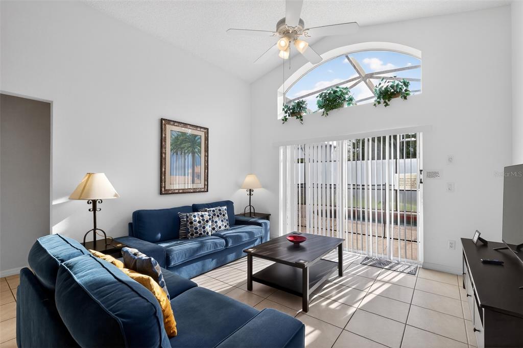 A living room features blue sofas, a coffee table, tile floors, and a vaulted ceiling — 1255 SEASONS BOULEVARD, KISSIMMEE, FL