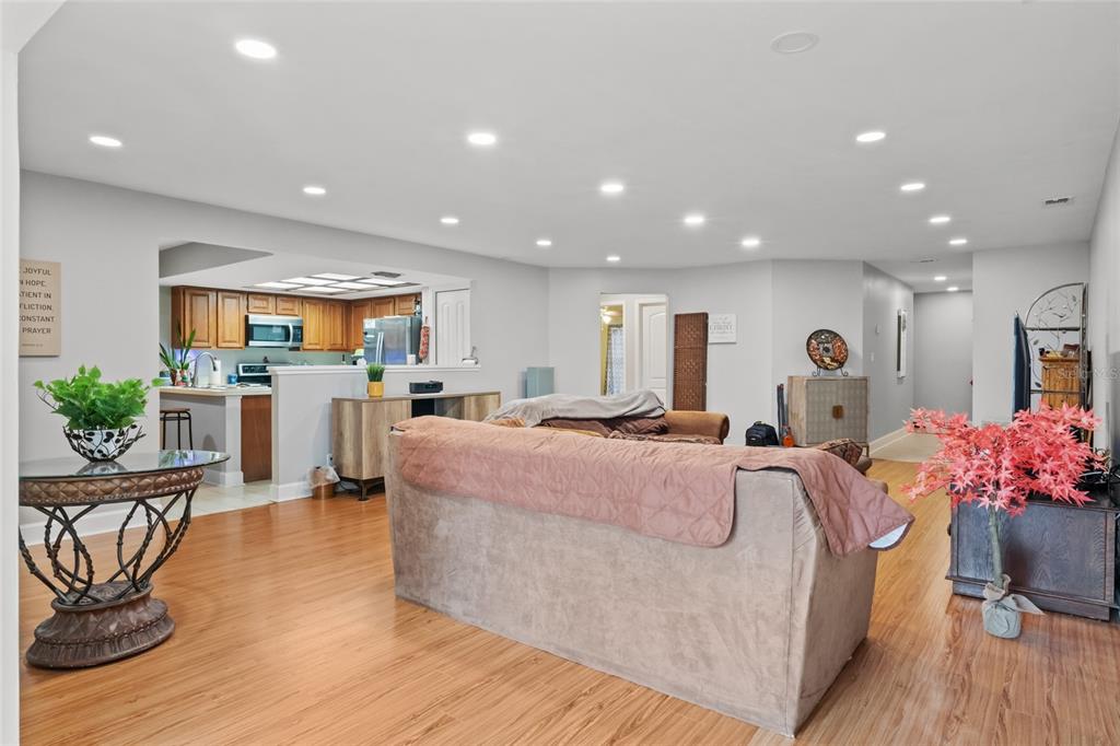 A living room with light wood flooring, recessed lighting, and an open view of the kitchen — 13140 VILLAGE CHASE CIRCLE UNIT 13140, TAMPA, FL