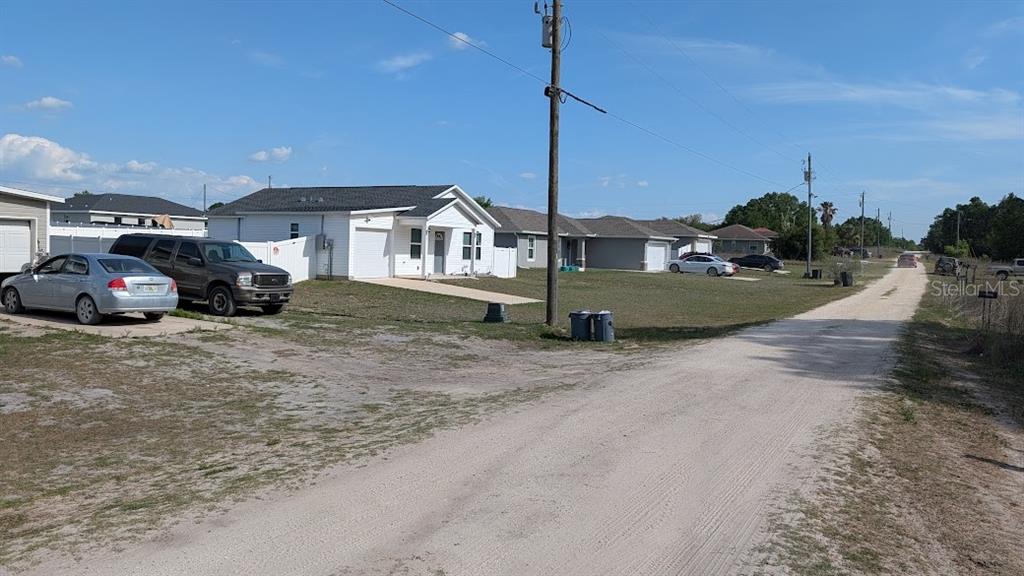A gravel road leads past several single-story houses with driveways and parked vehicles — Lot 88 SW 152 ND COURT, OCALA, FL