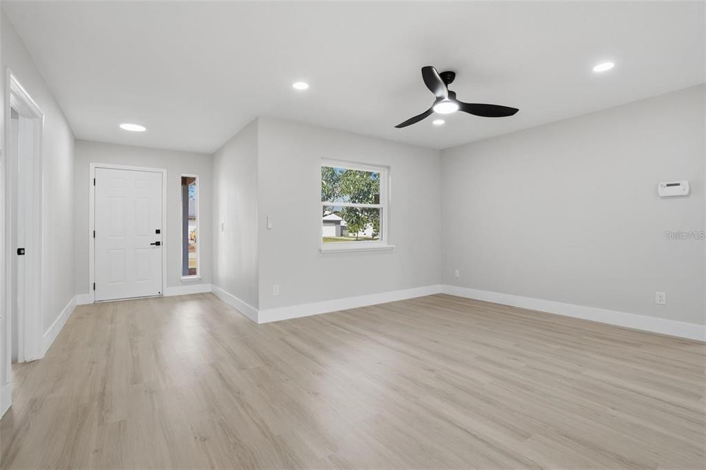 An empty room with light gray walls, wood-look flooring, a ceiling fan, and a front door — 2843 CALICO COURT, ORLANDO, FL