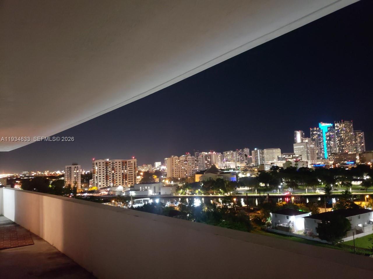 A balcony overlooks a city skyline at night with illuminated high-rise buildings — 36 NW 6th Ave # 906, Miami FL 33128, MIAMI, FL