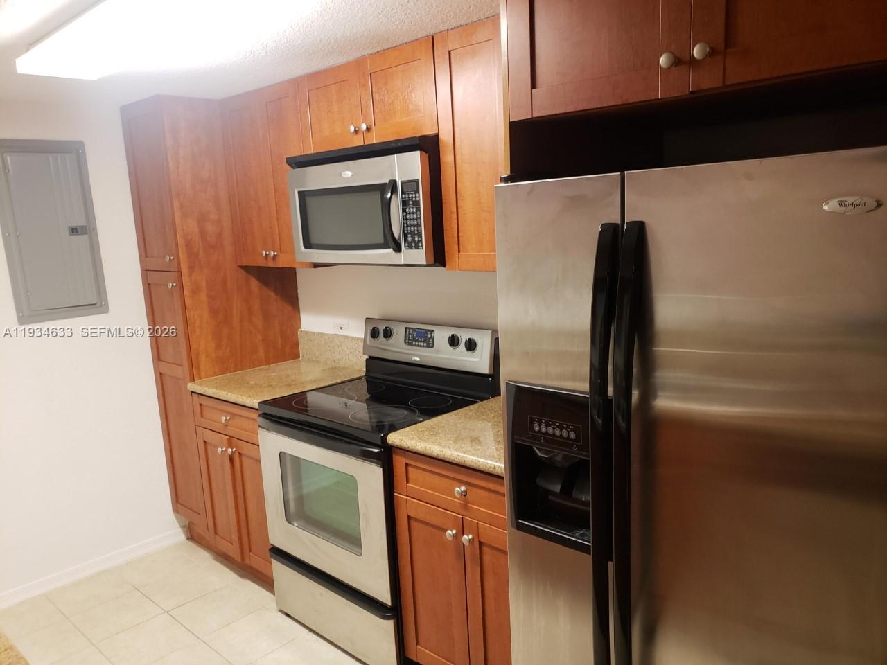 A kitchen features stainless steel appliances, wood cabinets, and granite countertops — 36 NW 6th Ave # 906, Miami FL 33128, MIAMI, FL