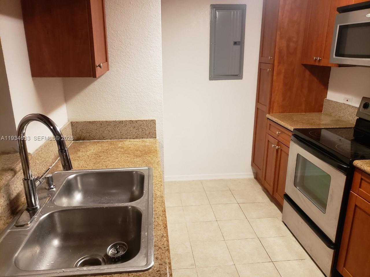 A kitchen features a double-basin sink, wood cabinets, granite countertops, and stainless steel appliances — 36 NW 6th Ave # 906, Miami FL 33128, MIAMI, FL