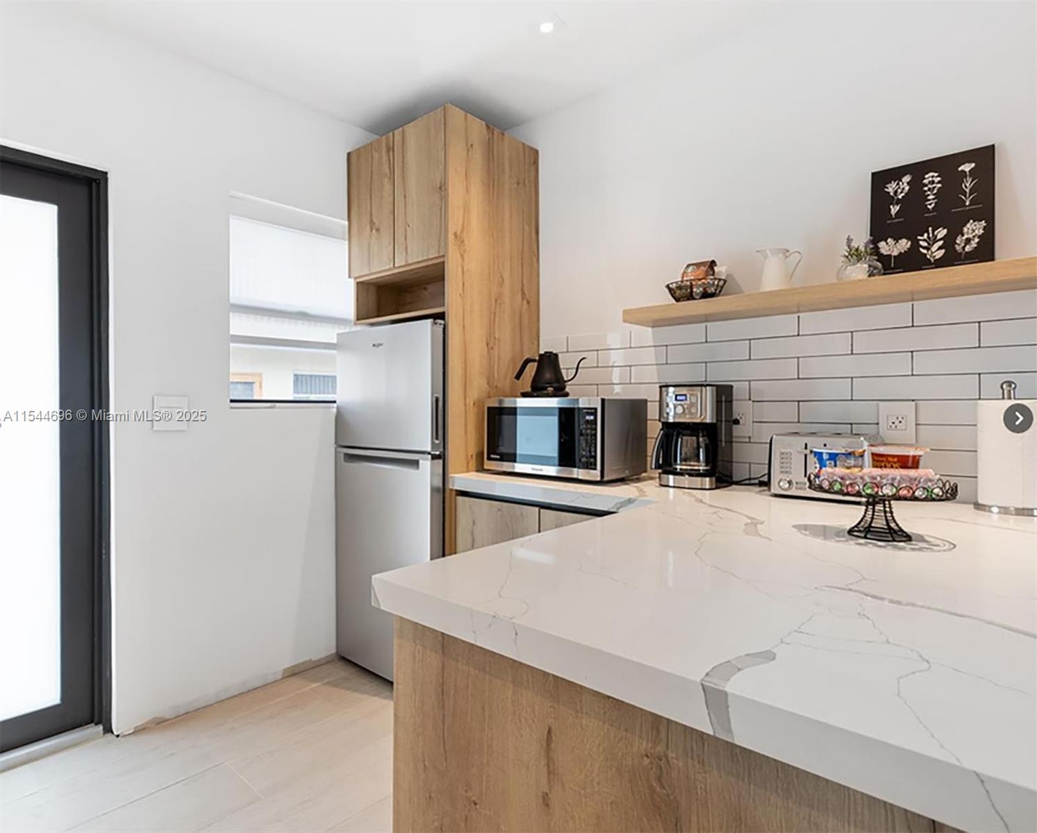 A modern kitchen features light wood cabinetry, white marble-look countertops, and white subway tile backsplashes — 740 SW 9th St # 2, Miami FL 33130, MIAMI, FL