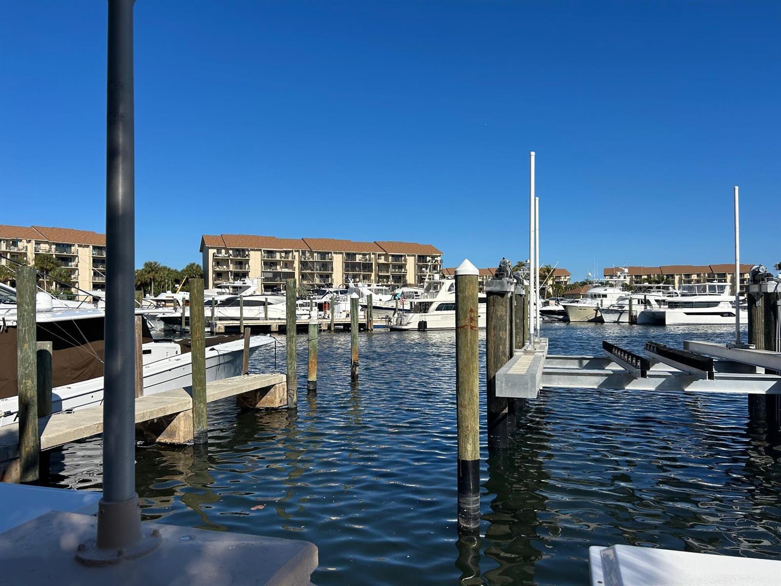 A marina with several docked yachts and multi-story residential buildings under a clear blue sky — 2601 Marina Isle Way # 105, Jupiter FL 33477, JUPITER, FL