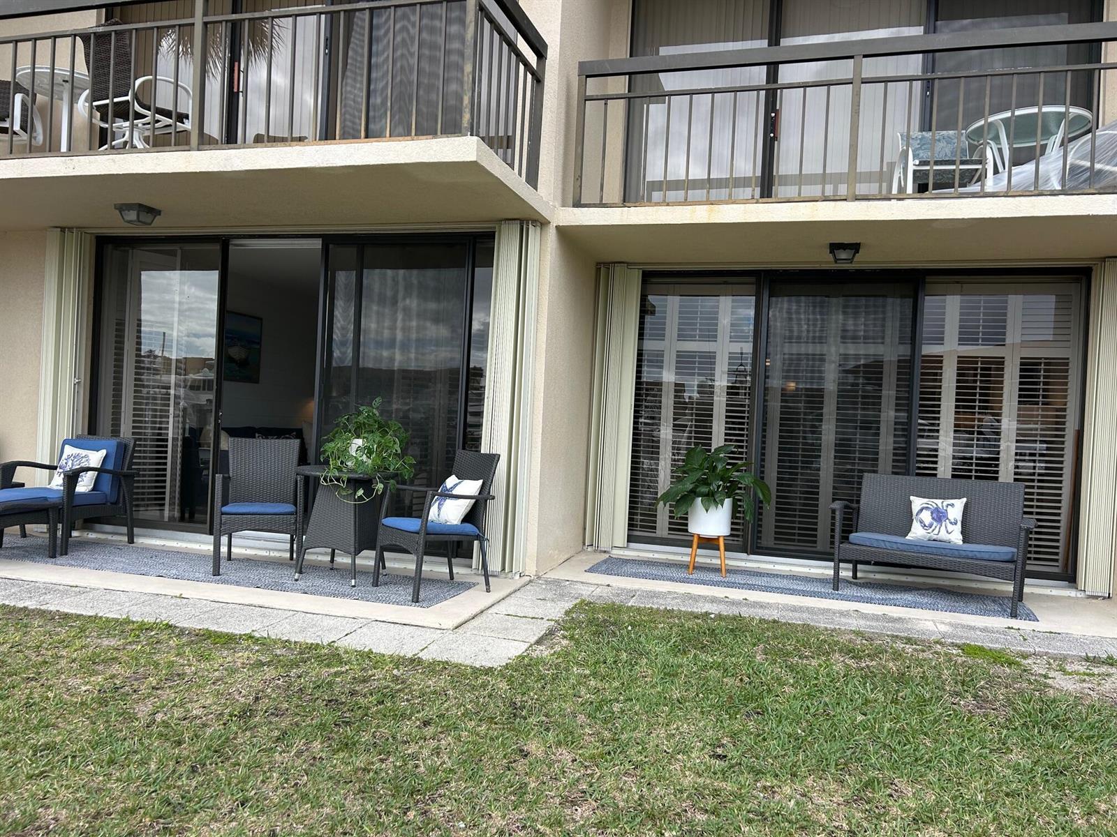 Two ground-floor patio units feature sliding glass doors, outdoor furniture, and a shared grassy lawn — 2601 Marina Isle Way # 105, Jupiter FL 33477, JUPITER, FL