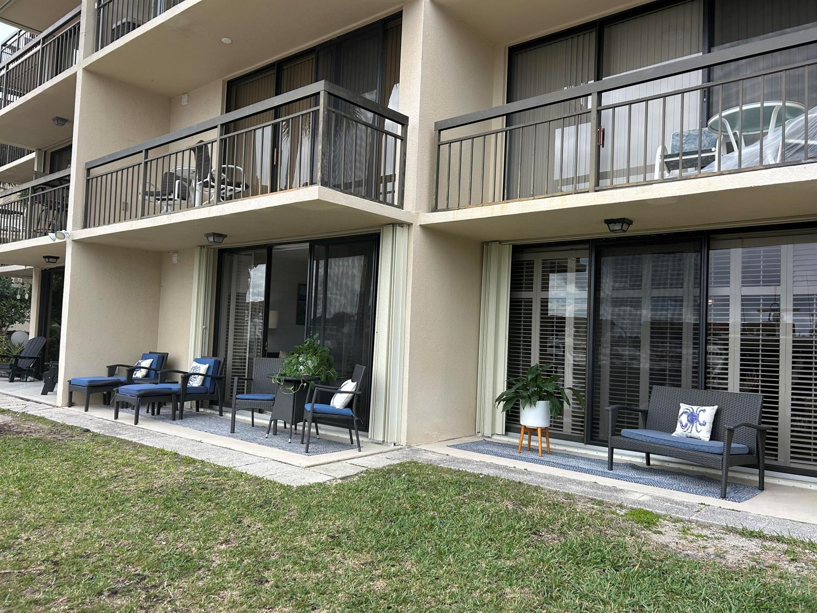 The exterior of a multi-story building features ground-level patios with outdoor furniture and balconies above — 2601 Marina Isle Way # 105, Jupiter FL 33477, JUPITER, FL