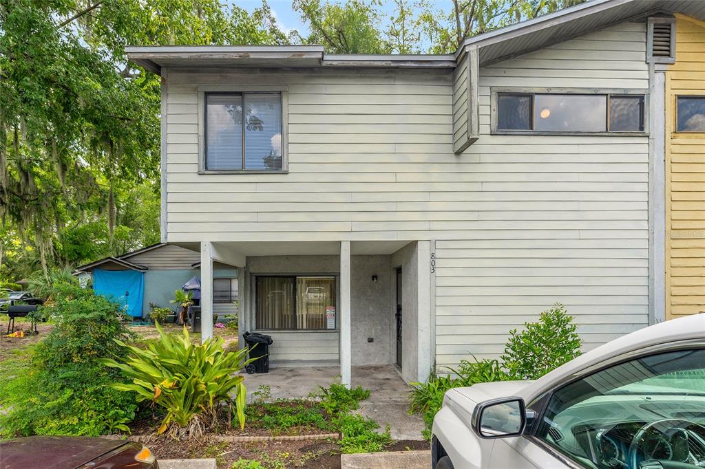 A two-story townhouse with light-colored horizontal siding and a covered ground-level entryway — 803 SW 2ND TERRACE, GAINESVILLE, FL