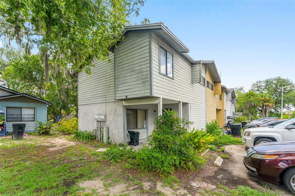 A two-story townhouse exterior with light-colored siding, a ground-level patio, and adjacent parking — 803 SW 2ND TERRACE, GAINESVILLE, FL