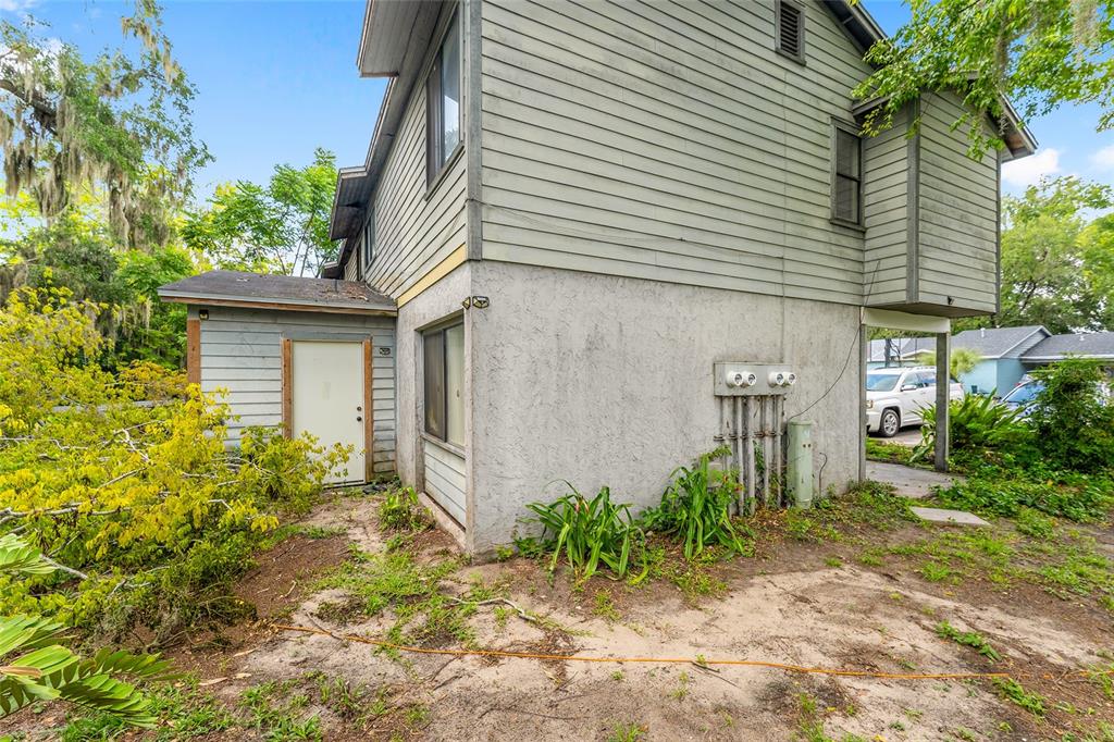 The exterior of a two-story house features gray siding, a stucco base, and utility meters — 803 SW 2ND TERRACE, GAINESVILLE, FL