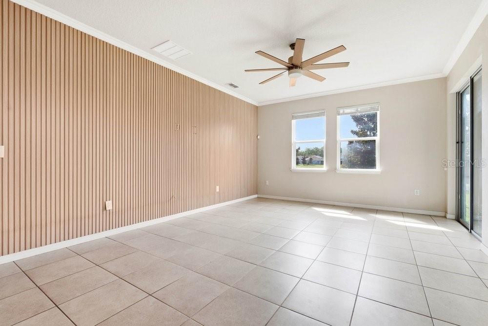 A living room features light-colored tile floors, a slatted wood accent wall, and a ceiling fan — 1494 CHELSEA MANOR CIRCLE, DELAND, FL