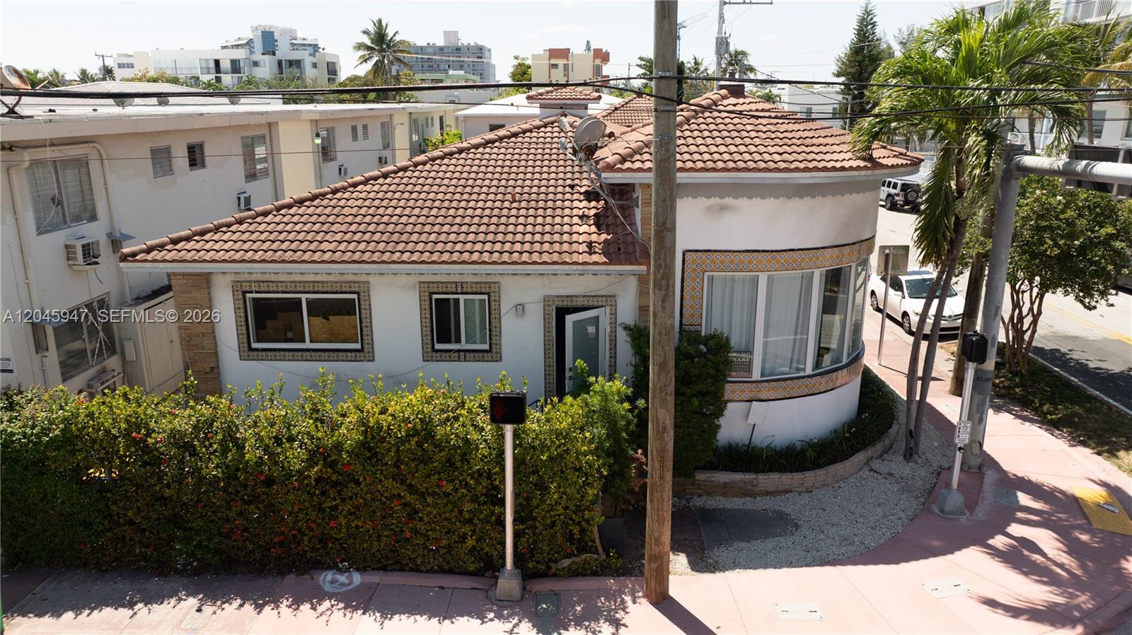 An exterior view of a white, single-story building with a curved wall and tile roof — 7640 Harding Ave, Miami Beach FL 33141, MIAMI BEACH, FL