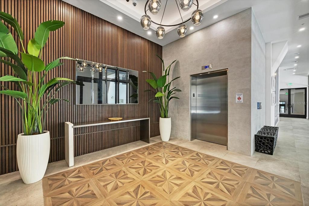 A modern building lobby features a wood-slat wall, an elevator, and patterned wood flooring — 33 S PALM AVENUE UNIT 1503, SARASOTA, FL