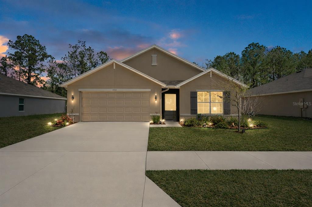 A single-story suburban house with a tan stucco exterior, a two-car garage, and a driveway — 5230 DIANTHA WAY, BROOKSVILLE, FL