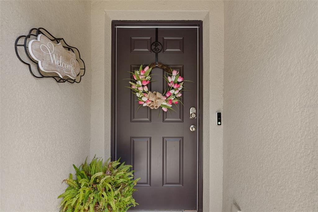 A dark brown front door with a floral wreath sits in a beige entryway — 5230 DIANTHA WAY, BROOKSVILLE, FL