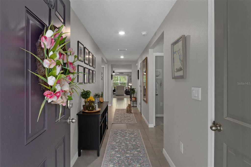 A view from a doorway looking down a tiled hallway toward a living area — 5230 DIANTHA WAY, BROOKSVILLE, FL