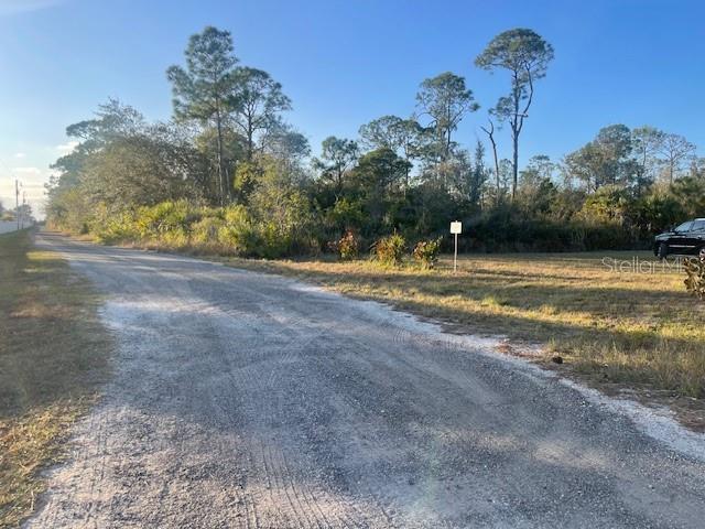A dirt road leads to a vacant, wooded lot with a small sign — 4930 PELICAN DRIVE, PUNTA GORDA, FL