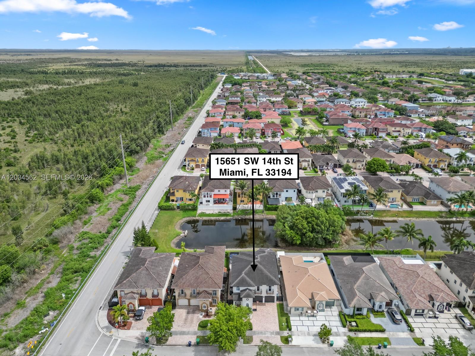 An aerial view shows a suburban neighborhood with a two-story house highlighted by a pointer — 15651 SW 14th St, Miami FL 33194, MIAMI, FL