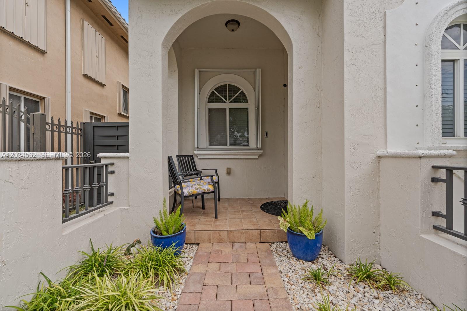 A paved walkway leads to a covered entryway with two chairs and two potted plants — 15651 SW 14th St, Miami FL 33194, MIAMI, FL