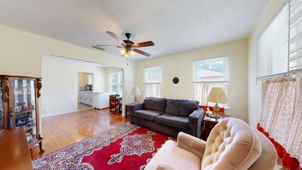 A living room features a red patterned rug, a dark sofa, and hardwood floors — 125 N CAROLINE STREET, DAYTONA BEACH, FL