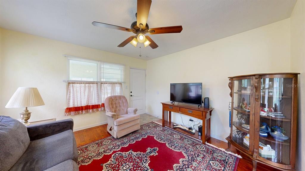 A living room features a ceiling fan, a television on a console, and a red rug — 125 N CAROLINE STREET, DAYTONA BEACH, FL