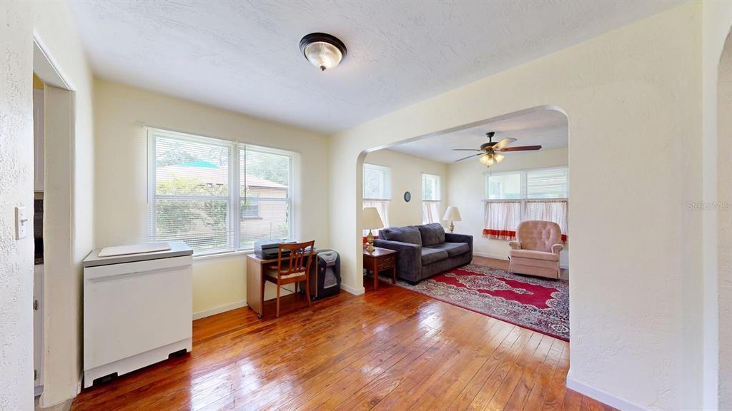 A dining area with hardwood floors leads into a living room with a red rug — 125 N CAROLINE STREET, DAYTONA BEACH, FL