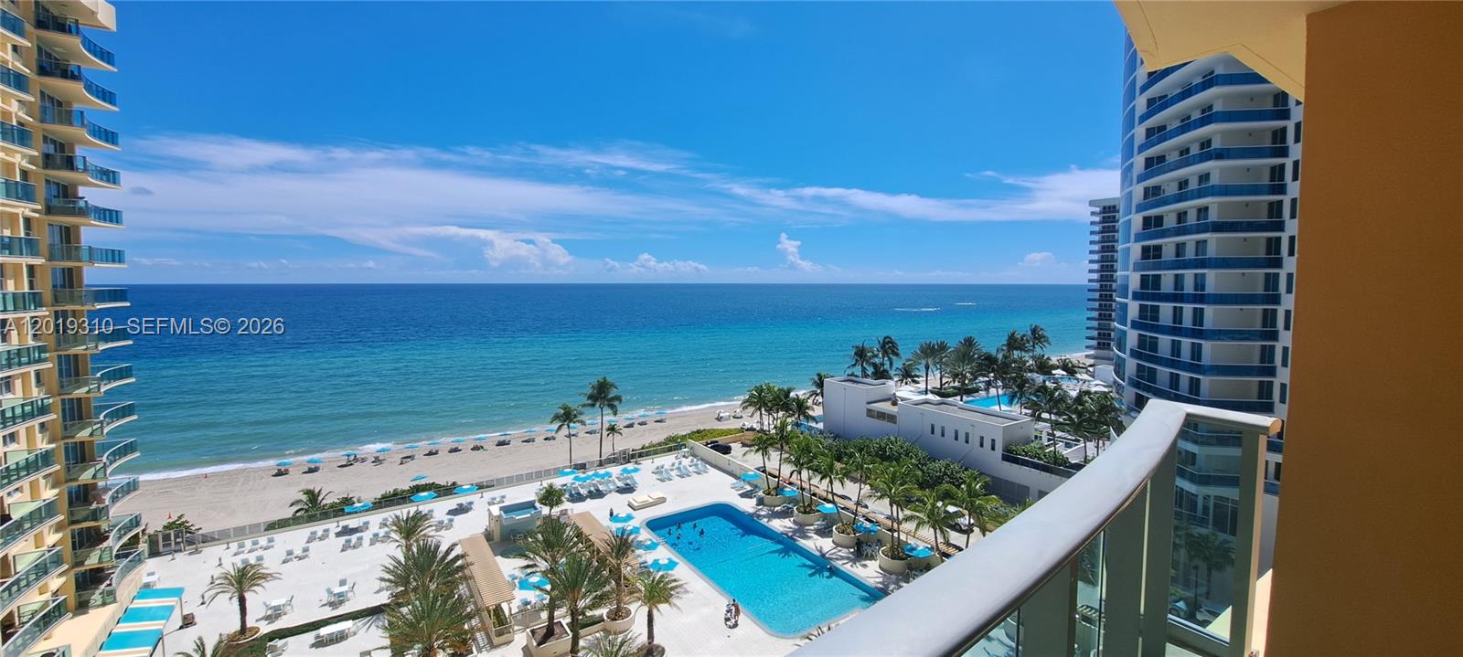 A high-angle view from a balcony overlooks a swimming pool, beach, and the ocean — 2501 S Ocean Dr # 1021, Hollywood FL 33019, HOLLYWOOD, FL