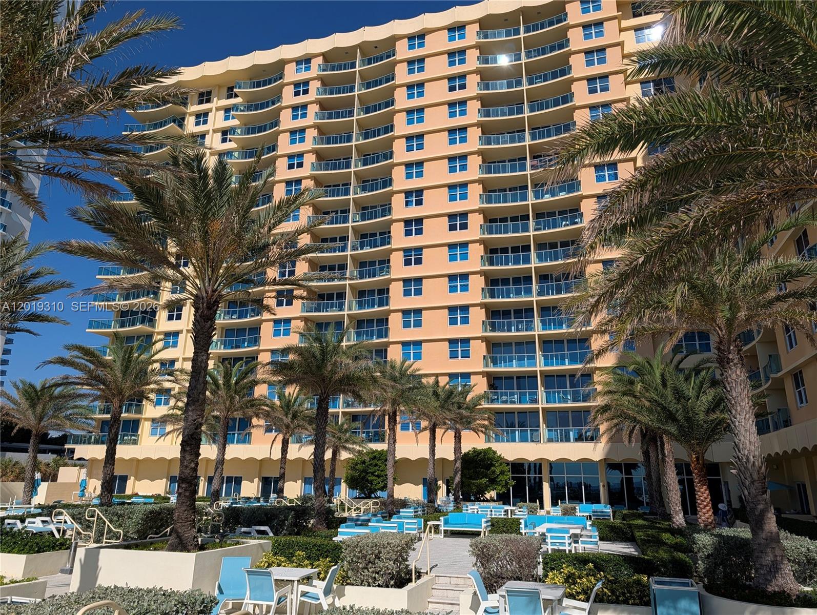 A tall, tan, multi-story residential building features numerous balconies and is surrounded by palm trees — 2501 S Ocean Dr # 1021, Hollywood FL 33019, HOLLYWOOD, FL