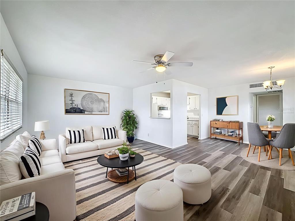 A living room and dining area feature white walls, wood-look flooring, and neutral-toned furniture — 202 BEDFORD TRAIL UNIT 103, SUN CITY CENTER, FL