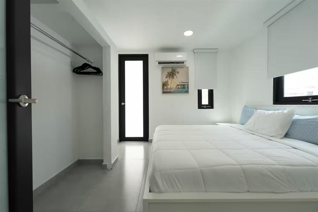 A bedroom with white walls, a white bed, a walk-in closet, and a glass door — 149 CALLE DELBREY, SAN JUAN, PR