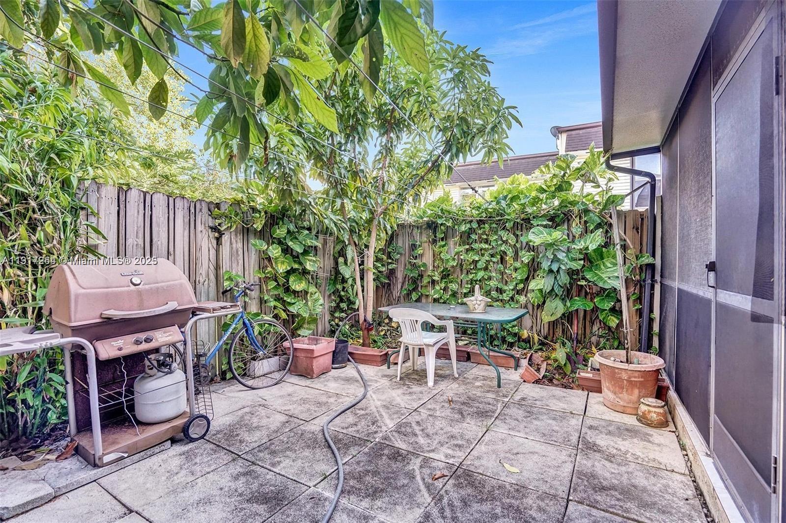 A paved patio features a grill, a bicycle, a table with chairs, and lush greenery — 2701 N 34th Ave # 1D, Hollywood FL 33021, HOLLYWOOD, FL