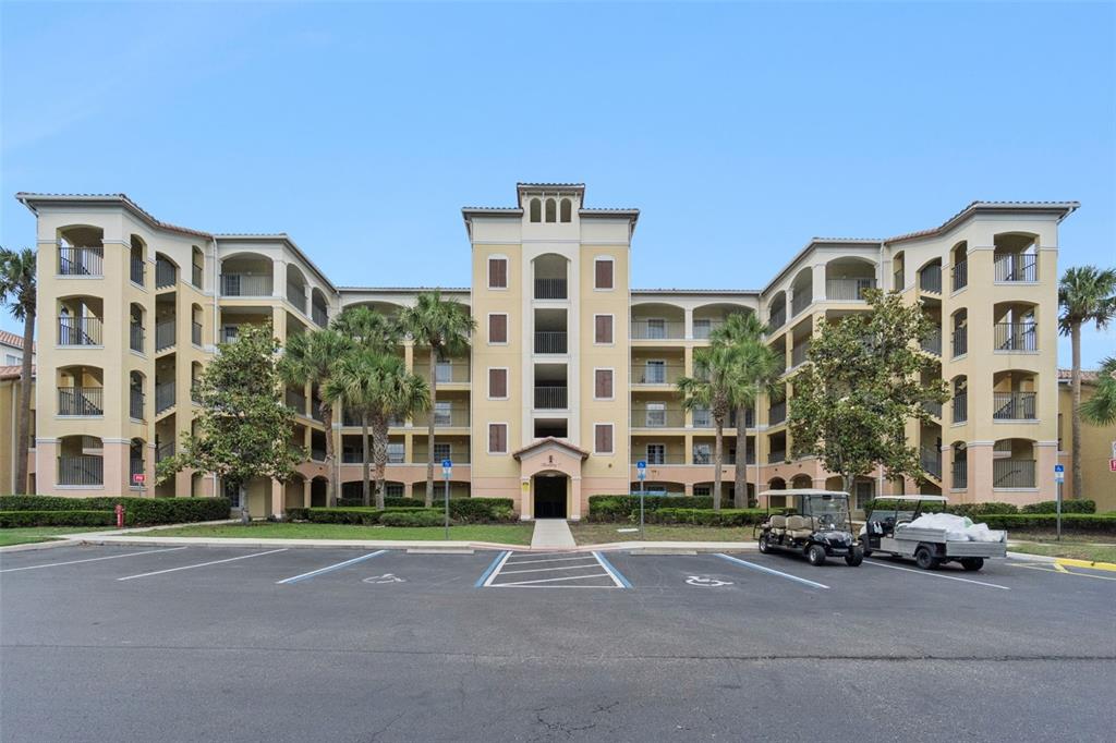 A multi-story apartment building with a central entrance and a parking lot in front — 8774 WORLDQUEST BOULEVARD UNIT 7103, ORLANDO, FL