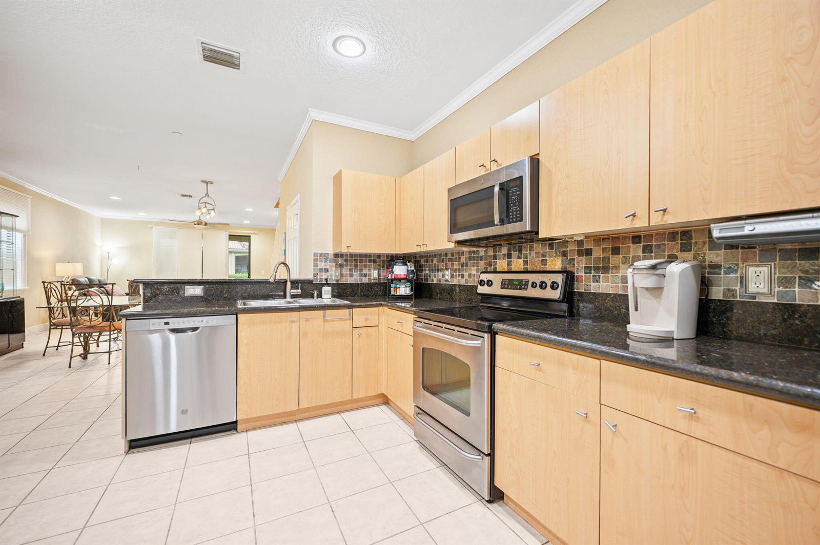A kitchen features light wood cabinets, dark granite countertops, stainless steel appliances, and tile flooring — 4212 Vineyard Circle, Weston FL 33332, WESTON, FL