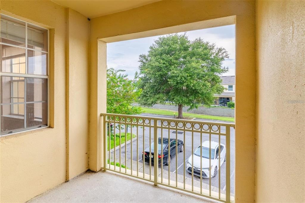 A tan multi-story apartment building exterior features a central staircase and surrounding green trees — 709 TERRACE RIDGE CIRCLE UNIT 709, DAVENPORT, FL