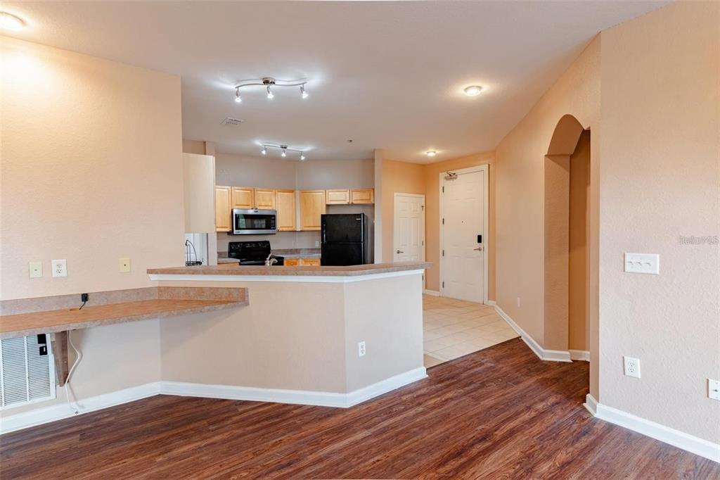 A living room with a gray sectional, yellow armchair, built-in desk, and open kitchen — 709 TERRACE RIDGE CIRCLE UNIT 709, DAVENPORT, FL
