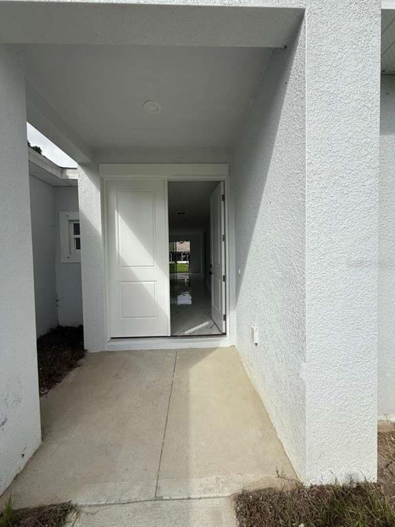 A white front door opens into a home with light-colored flooring and a covered entryway — 1121 COGAN DRIVE SE, PALM BAY, FL