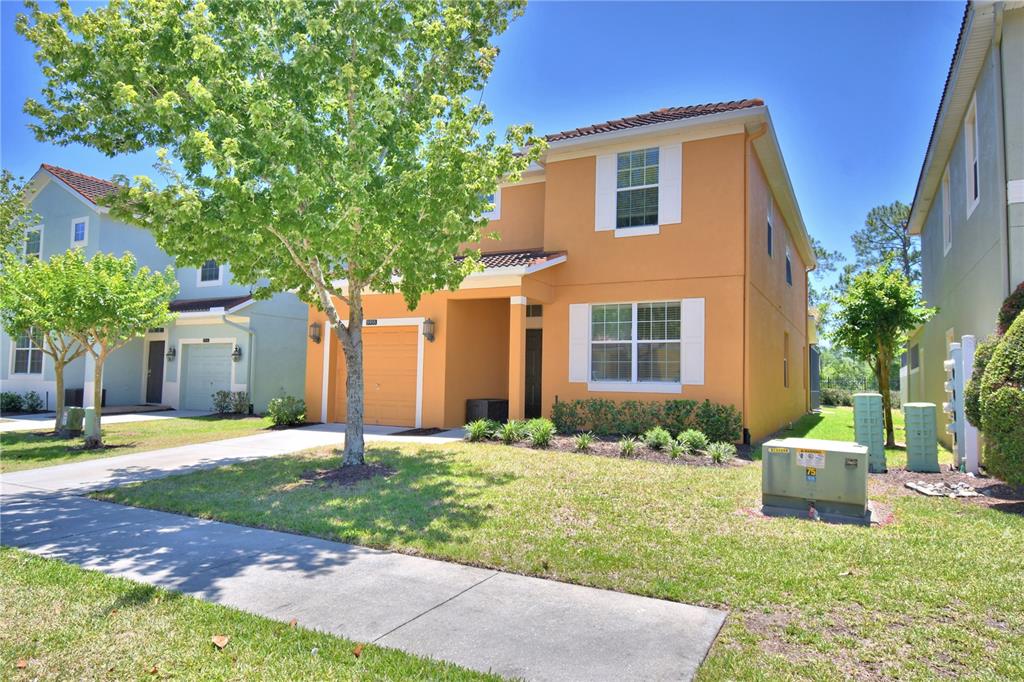 A two-story orange stucco house with a single-car garage and a front lawn — 8958 SUGAR PALM ROAD, KISSIMMEE, FL