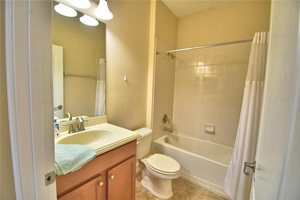 A bathroom features a vanity with a sink, a toilet, and a shower-tub combination — 8958 SUGAR PALM ROAD, KISSIMMEE, FL