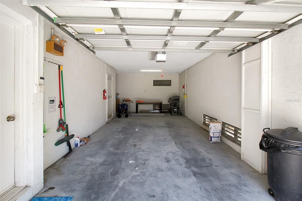 A long, empty garage with concrete floors, a white ceiling, and a workbench at the back — 535 FOREST WAY, LONGBOAT KEY, FL