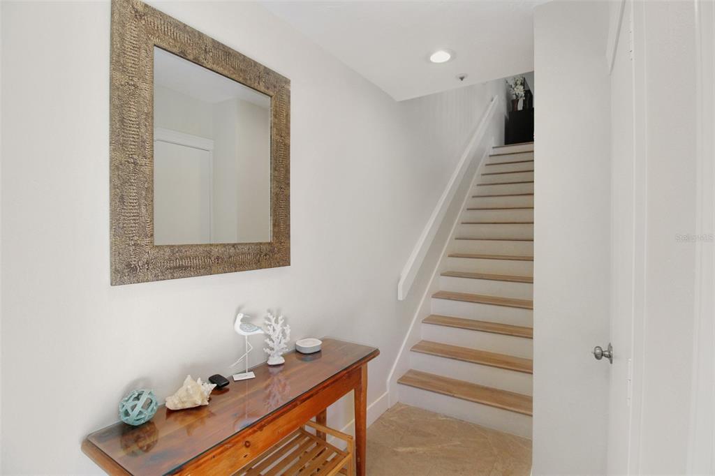 A wooden console table sits below a mirror in a hallway with stairs — 535 FOREST WAY, LONGBOAT KEY, FL