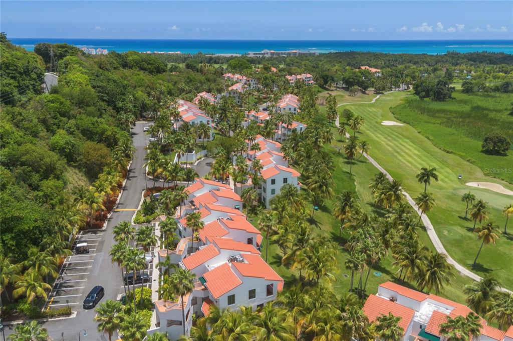 An aerial view shows a residential complex with red-tiled roofs next to a golf course — 2101 RIO MAR VILLAGE, RIO GRANDE, PR