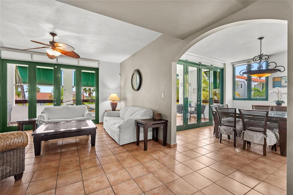 A living and dining area with tile floors, white sofas, and green-framed glass doors — 2101 RIO MAR VILLAGE, RIO GRANDE, PR
