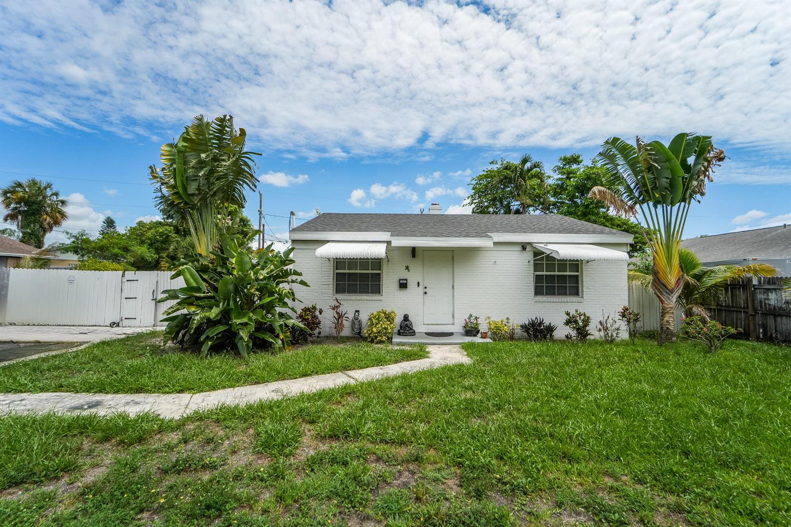 A white, single-story brick house features two large palm plants and metal window awnings — 1007 Charles Street, West Palm Beach FL 33401, WEST PALM BEACH, FL