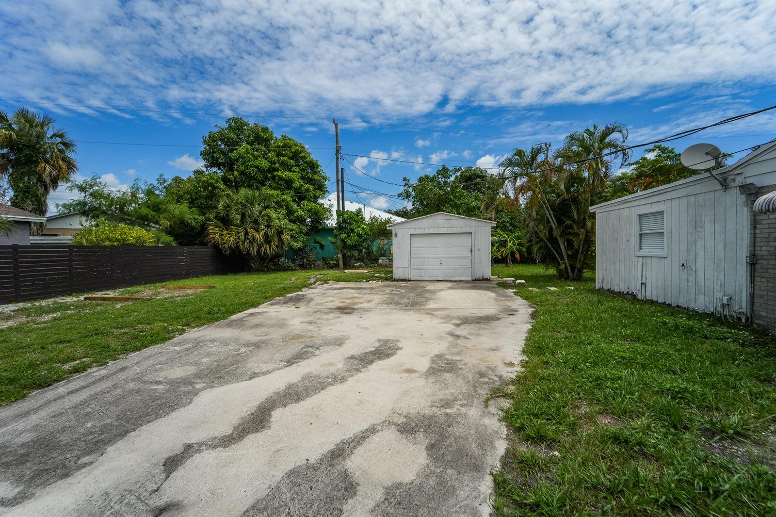 A detached garage sits at the end of a concrete driveway in a grassy backyard — 1007 Charles Street, West Palm Beach FL 33401, WEST PALM BEACH, FL