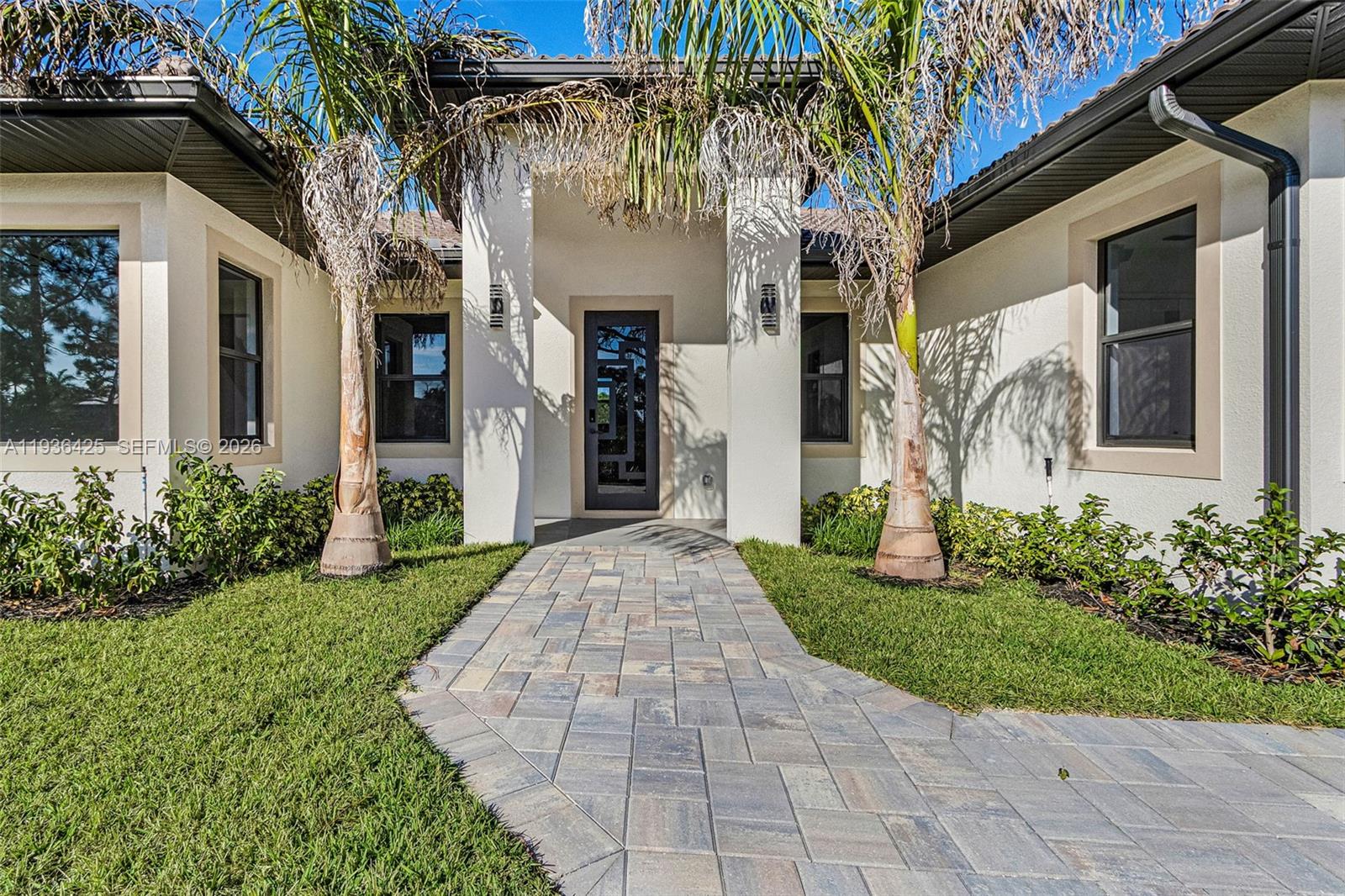 A paved walkway leads to the front entrance of a house with two palm trees — OTHER CITY - IN THE STATE OF FLORIDA, FL