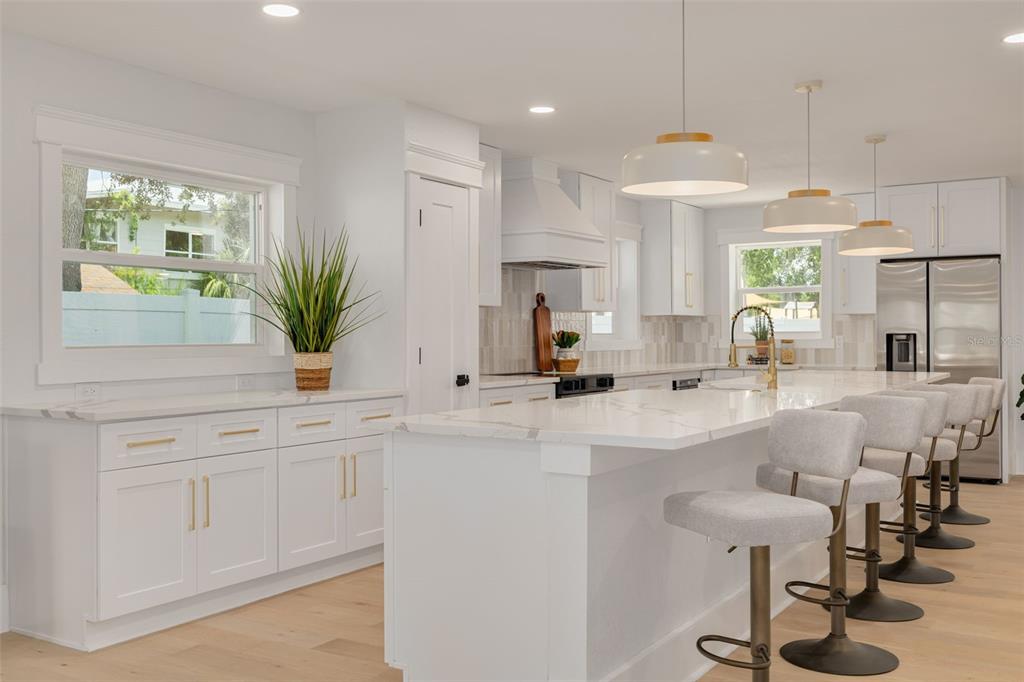 A bright kitchen features white cabinetry, a large marble-topped island, and four bar stools — 2528 4TH AVENUE S, ST PETERSBURG, FL