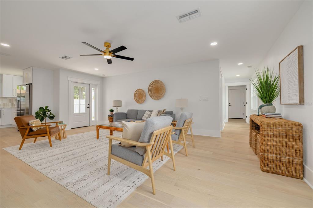 A bright living room features light wood floors, a gray sofa, and a ceiling fan — 2528 4TH AVENUE S, ST PETERSBURG, FL