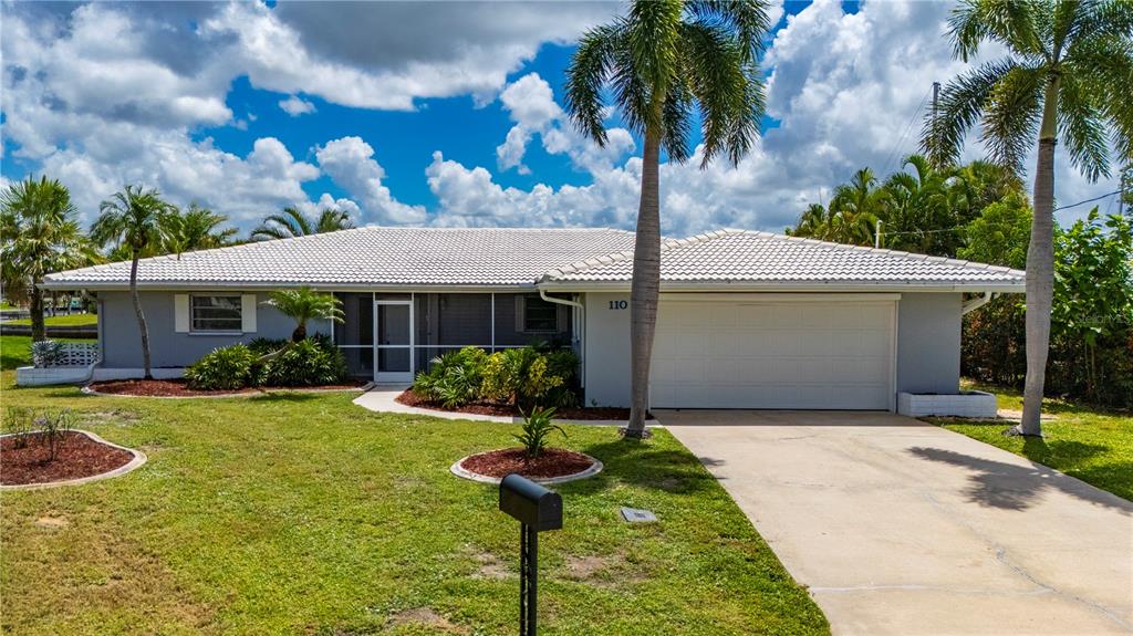 A single-story house with a white tile roof, gray exterior, and a two-car garage — 110 GULFVIEW ROAD, PUNTA GORDA, FL