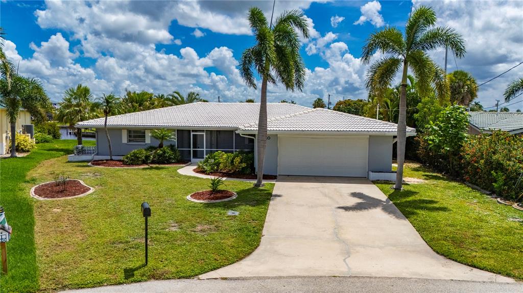 A single-story house with a white tiled roof, a concrete driveway, and several palm trees — 110 GULFVIEW ROAD, PUNTA GORDA, FL