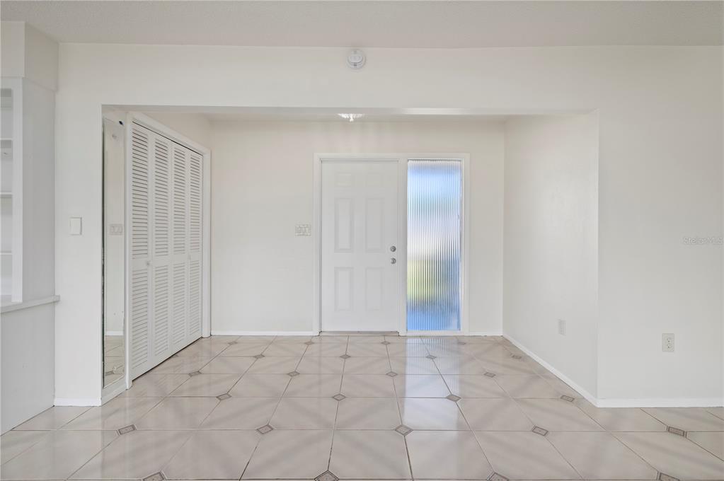 An entryway with white walls, tiled flooring, a white front door, and a louvered closet — 110 GULFVIEW ROAD, PUNTA GORDA, FL